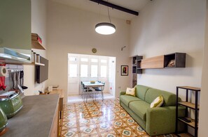 A spacious living area with a green sofa, a dining table with chairs, and a kitchen area with a microwave and utensils. - Stylish traditional house with sun terrace TELL1-1 (Birgu)