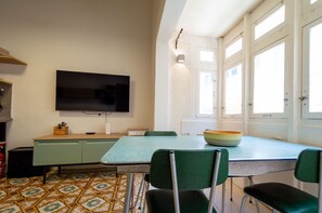 A dining area with a table, chairs, a television, and a window with curtains. - Stylish traditional house with sun terrace TELL1-1 (Birgu)