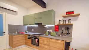 A modern kitchen with wooden cabinets, a built-in oven, a sink, and a countertop with a kettle and toaster. - Stylish traditional house with sun terrace TELL1-1 (Birgu)