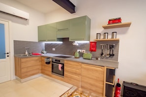 Eine moderne Küche mit Holzausstattung, Backofen, Spüle und einer Arbeitsplatte mit Wasserkocher und Toaster.