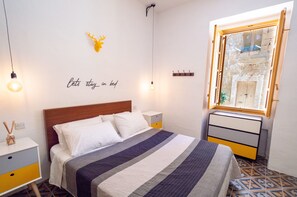 A neatly arranged bedroom with a bed, bedside tables, a wall-mounted mirror, and a decorative deer head. - Stylish traditional house with sun terrace TELL1-1 (Birgu)