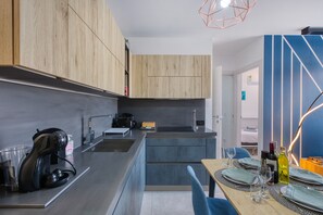 A modern kitchen with wooden cabinets, a built-in oven, and a dining area with a table set for two. - Beautiful penthouse with terrace & jacuzzi WVID1-2 (Msida)