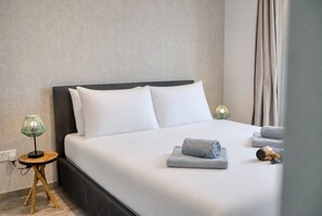 A neatly made bed with white linens, a bedside lamp, and towels on the side. - Beautiful penthouse with terrace & jacuzzi WVID1-2 (Msida)