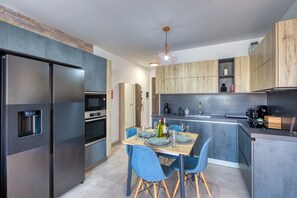 A modern kitchen with a built-in refrigerator, oven, and microwave. There is a dining table with chairs and a hanging light fixture. - Beautiful penthouse with terrace & jacuzzi WVID1-2 (Msida)