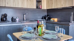 Une cuisine moderne avec des meubles en bois, une table à manger dressée avec des assiettes, des verres et des couverts, et une machine à café.