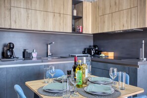 A modern kitchen with wooden cabinets, a dining table set with plates, glasses, and cutlery, and a coffee machine. - Beautiful penthouse with terrace & jacuzzi WVID1-2 (Msida)