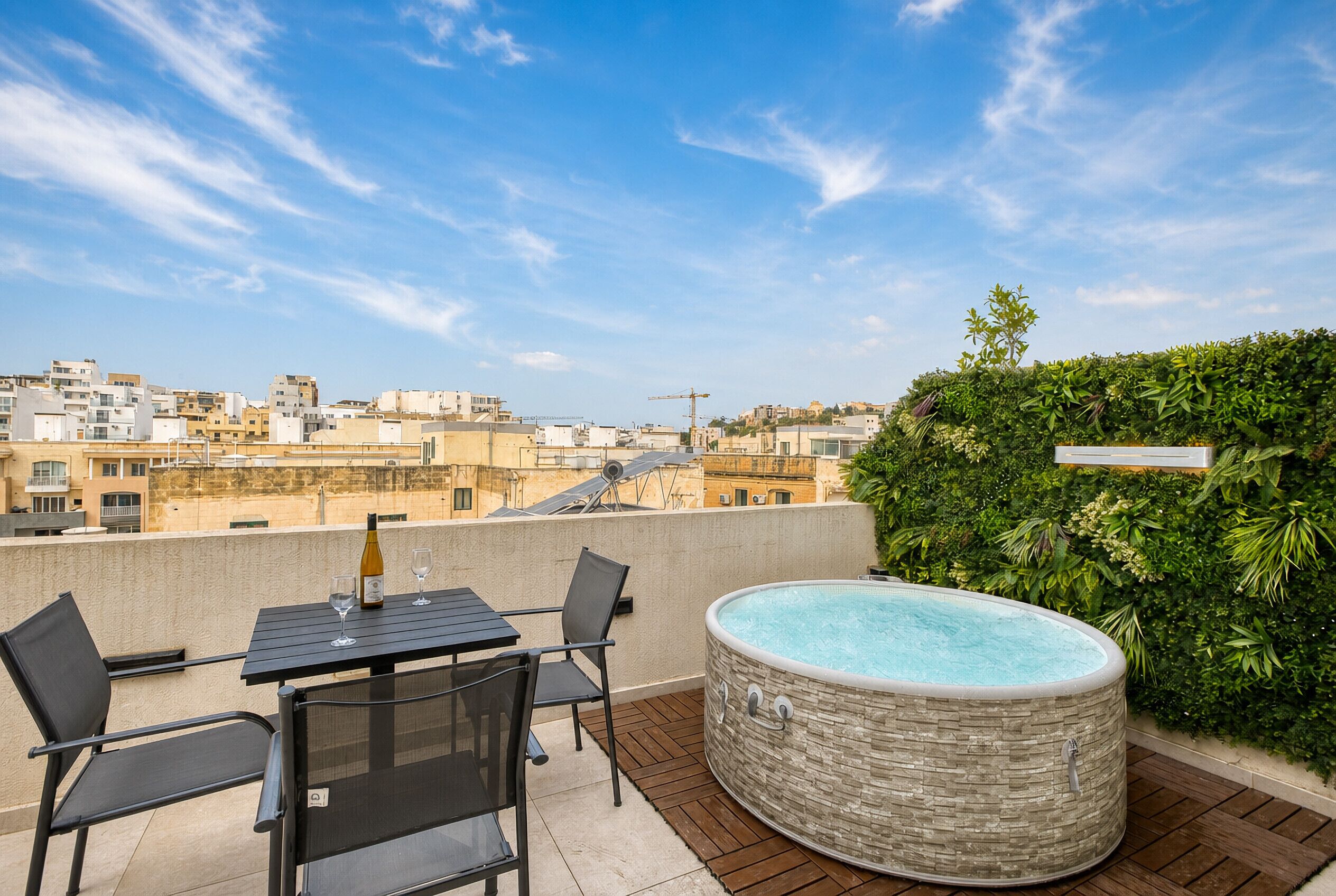 Une terrasse sur le toit avec une table, des chaises et un jacuzzi.