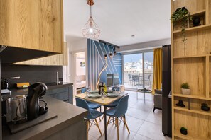 A modern kitchen with a built-in coffee machine, a dining area with blue chairs, and a view of the city through large windows. - Beautiful penthouse with terrace & jacuzzi WVID1-2 (Msida)