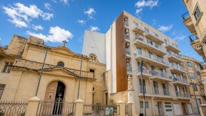 Une église historique à la façade traditionnelle et un immeuble d’appartements moderne doté de balcons et d’un bardage en bois vertical.