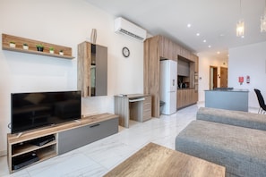 A modern living room with a flat-screen TV, wooden entertainment unit, and a grey sofa. - Spacious & bright 3 bedroom with balcony KDEB1-1 (Marsaxlokk)