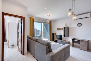 En moderne stue med sofa, fjernsyn og en balkon med udsigt.