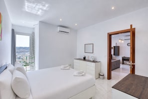 A modern bedroom with a large bed, a dresser, a mirror, and an air conditioning unit. - Spacious & bright 3 bedroom with balcony KDEB1-1 (Marsaxlokk)