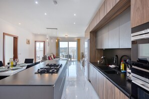 A modern kitchen with a central island, built-in appliances, and a view to the outside. - Spacious & bright 3 bedroom with balcony KDEB1-1 (Marsaxlokk)