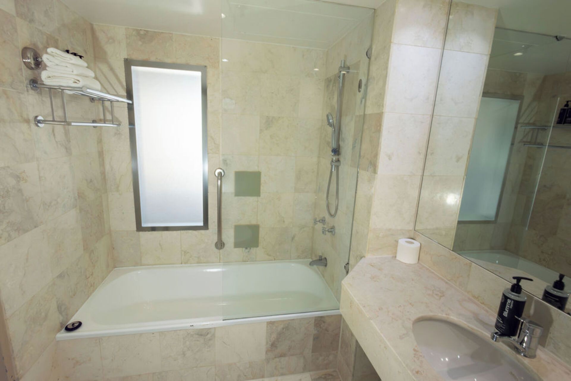 Un baño moderno con ducha de vidrio, bañera, tocador con lavamanos y espejo.