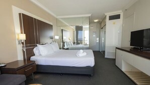 Ein Hotelzimmer mit Bett, Nachttisch, Fernseher und Spiegel.
