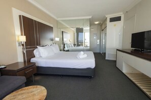 Ein Hotelzimmer mit Bett, Nachttisch, Fernseher und Spiegel.