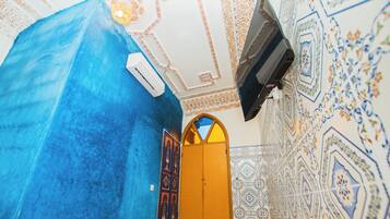 Een kamer met een blauwe wand, een wand met patroontegels, een houten deur en een plafond met decoratief ontwerp.