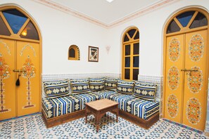 Una stanza con un divano ad angolo, un tavolino e due porte con decorazioni elaborate.