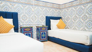 Quarto com duas camas, paredes estampadas e almofadas decorativas.