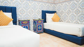 A bedroom with two beds, patterned walls, and decorative pillows.