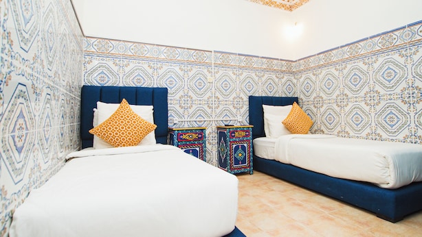 Quarto com duas camas, paredes estampadas e teto decorativo.