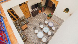 Um pátio com área de estar, uma mesa pequena e um vaso de planta.