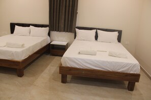 Habitación de hotel con dos camas individuales, cada una con estructura de madera y ropa de cama blanca.