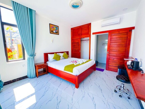 A hotel room with a bed, a desk, a wardrobe, and a window with curtains.