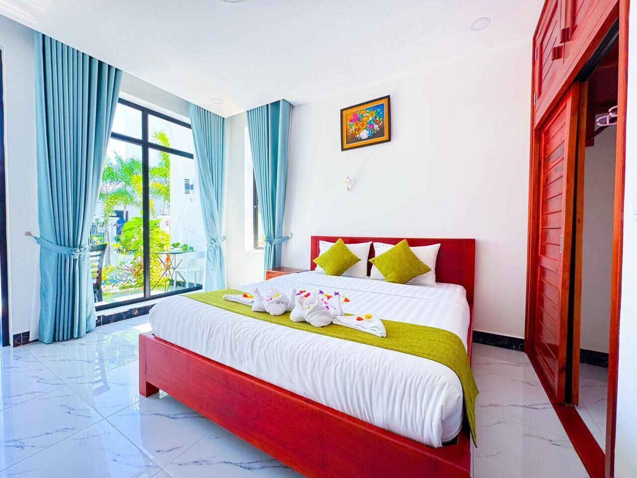Quarto de hotel com uma cama grande, cabeceira vermelha e vista para o verde lá fora.