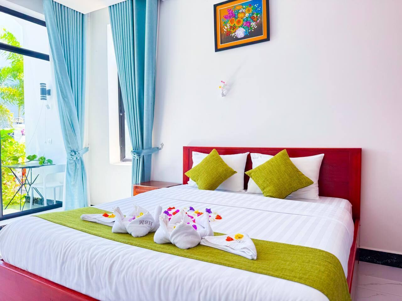 A hotel room with a bed, a window with curtains, a bedside table, and a wall-mounted picture.