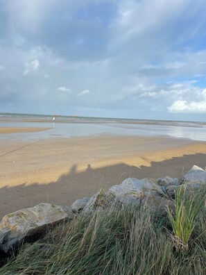 A beach with a rocky foreground and a distant view of the sea.