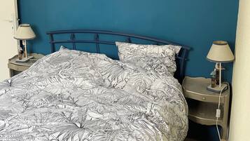 Un dormitorio con una cama, dos mesitas de noche, un cuadro colgado en la pared y una lámpara en cada mesita.