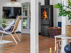 A cozy living area with a modern fireplace, a comfortable chair, and a television. - "Florida" -  from the sea by Interhome (Hals)