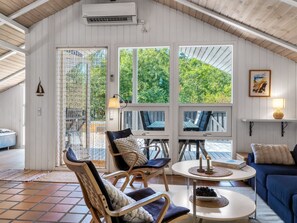 A cozy room with a large window, a dining table, two chairs, a sofa, and a small table with candles. - "Florida" -  from the sea by Interhome (Hals)