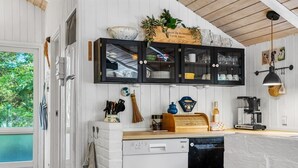 Una cocina equipada con lavavajillas, armarios y cafetera.