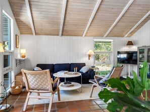 A cozy living room with a dark blue sofa, two wooden chairs, a round coffee table, and a television. - "Florida" -  from the sea by Interhome (Hals)