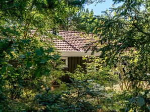 Een gebouw met een pannendak, omringd door weelderige beplanting.