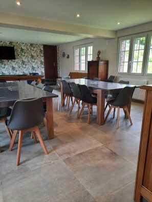 A spacious kitchen with a dining area, featuring a large island, multiple chairs, and a television mounted on the wall.