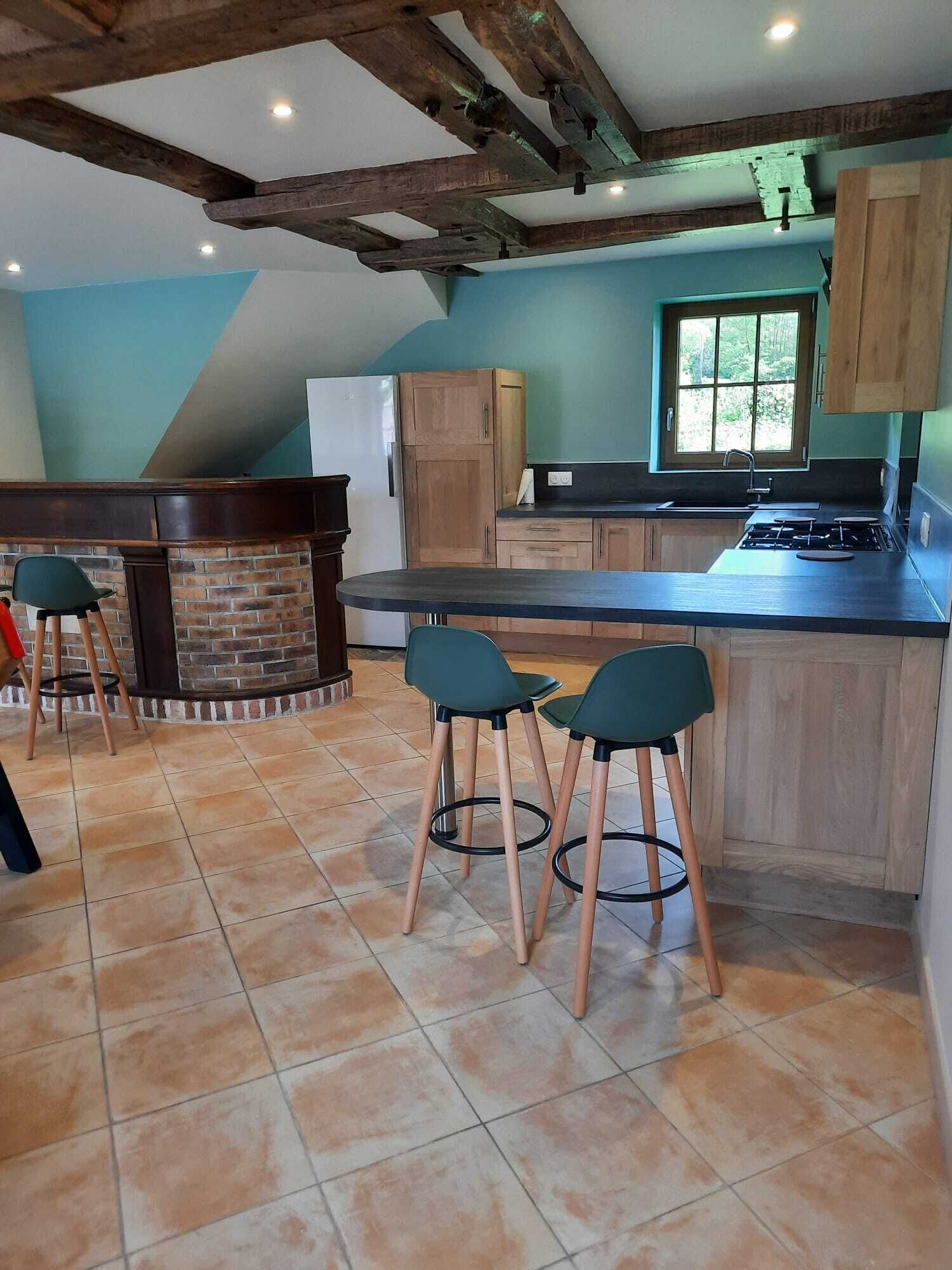 Una cocina con una isla central, armarios de madera, una pared de ladrillo y una ventana.