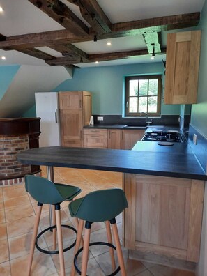 A kitchen with wooden cabinets, a black countertop, and a brick fireplace.