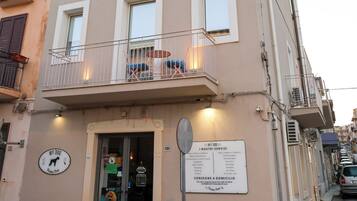 A building with a ground-floor shop, a balcony with a railing, and a signboard with text.