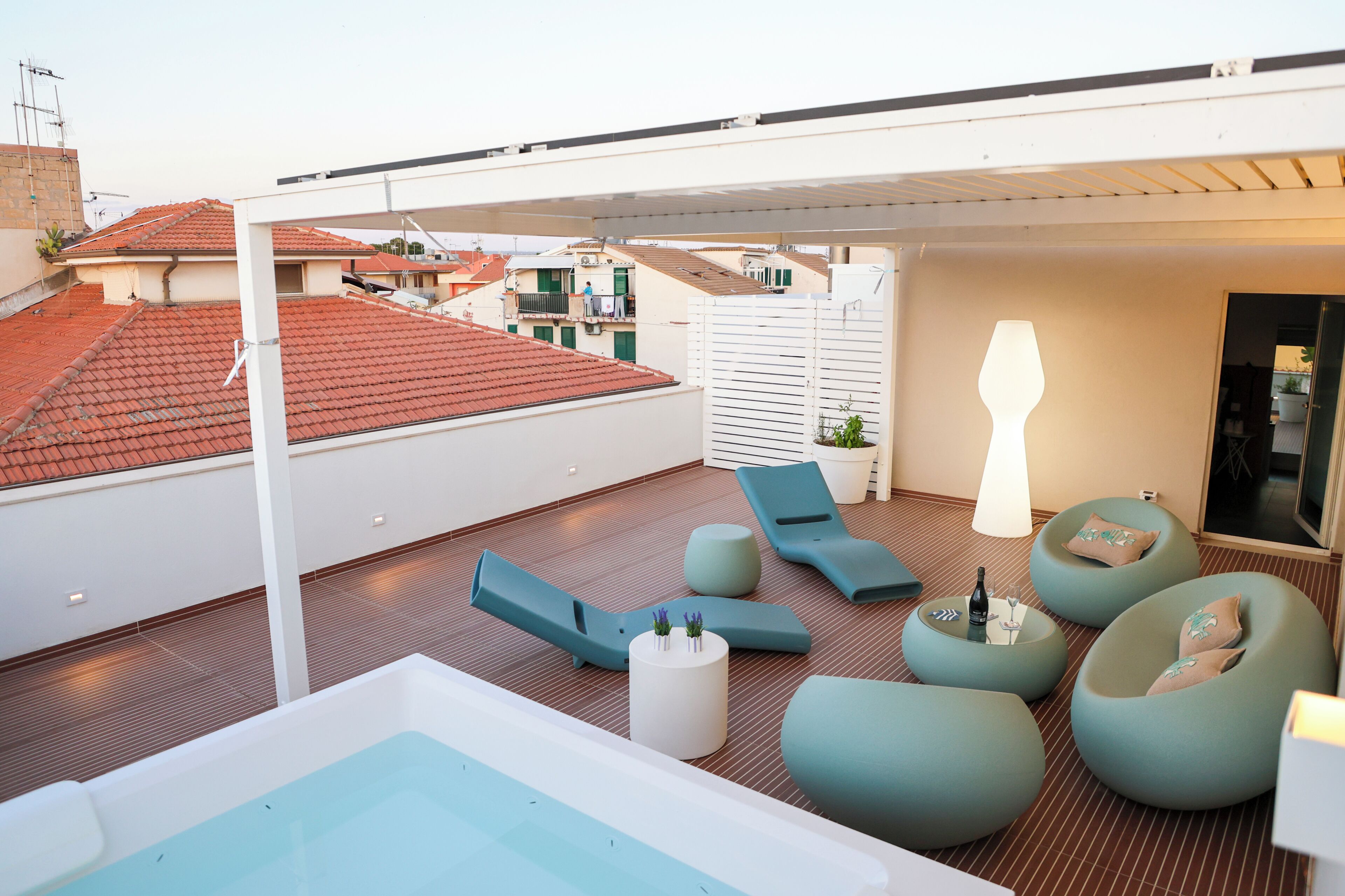 A rooftop terrace with a pool, lounge chairs, and a table with a bottle and glass.