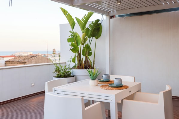 A white table with chairs on a balcony overlooking a beach. - Dimora Zahira Your Italian Escape (Marina di Ragusa)