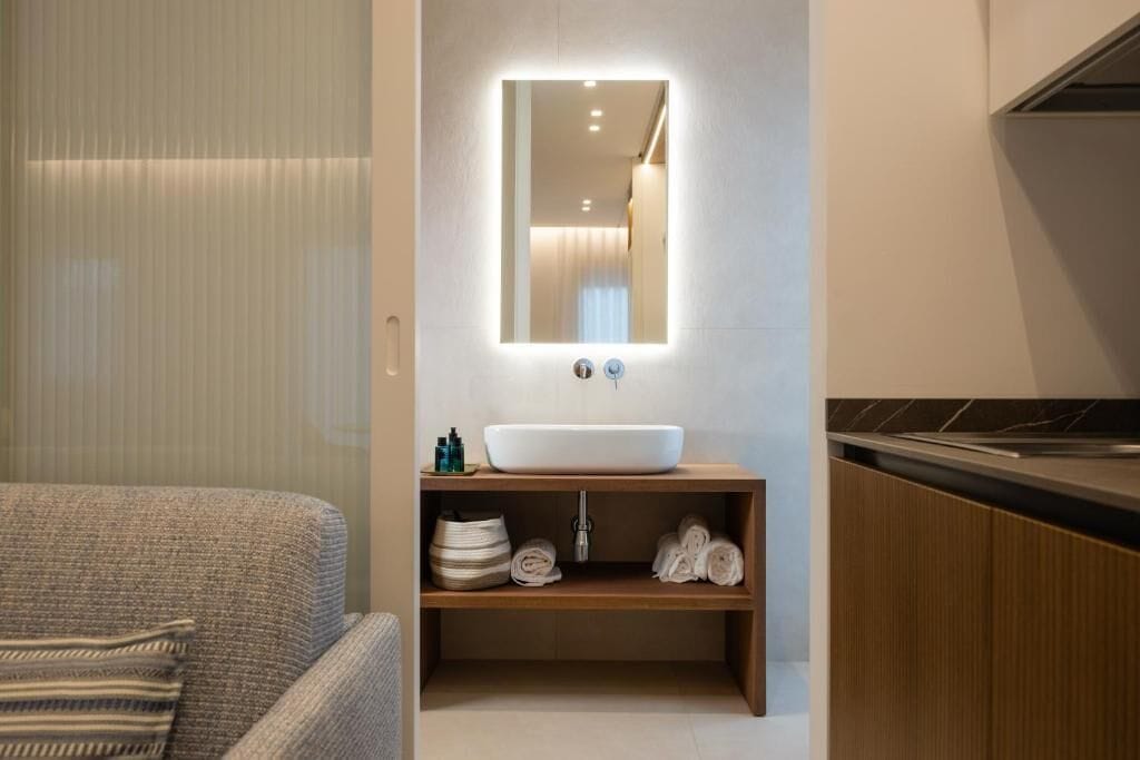 Un baño moderno con un espejo grande, un lavamanos sobre encimera y un mueble de tocador de madera.