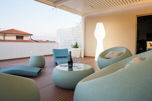 Un área de estar moderna al aire libre, con una mesa, sillas y una botella de vino.