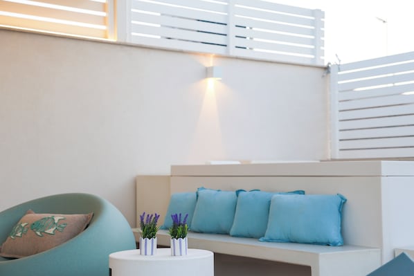 A modern living area with a sofa, cushions, a round table with decorative items, and a wall-mounted light.