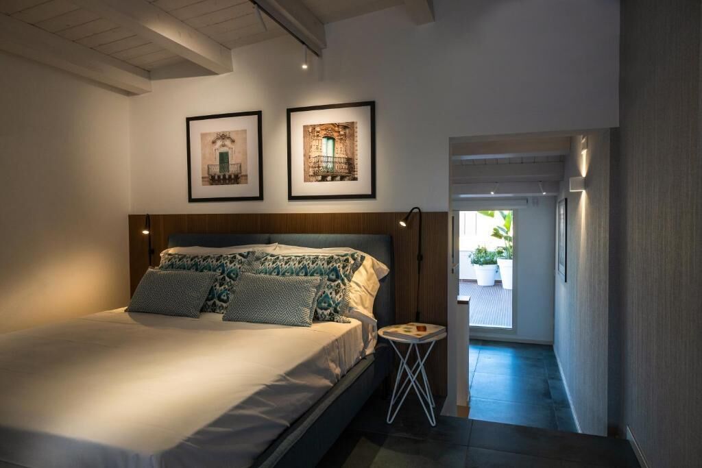 A bedroom with a bed, a nightstand, and two framed pictures on the wall.