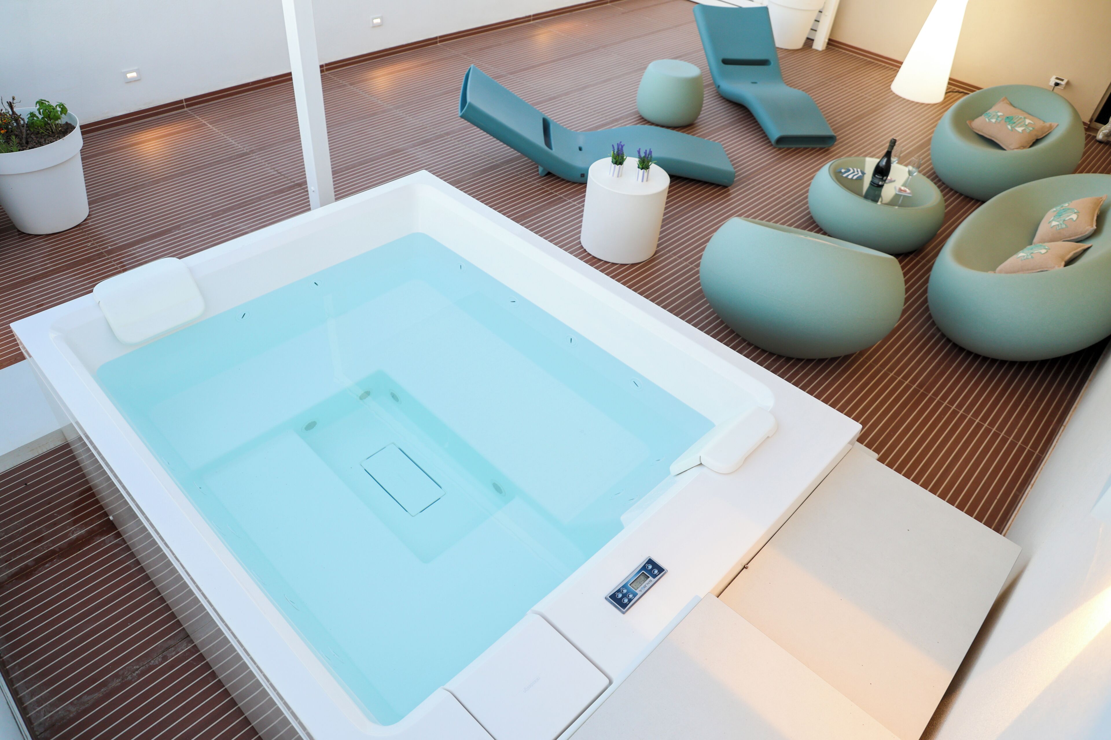 Ein moderner Wellnessbereich mit Whirlpool, Liegestühlen und einer kleinen Sitzecke mit Kissen.