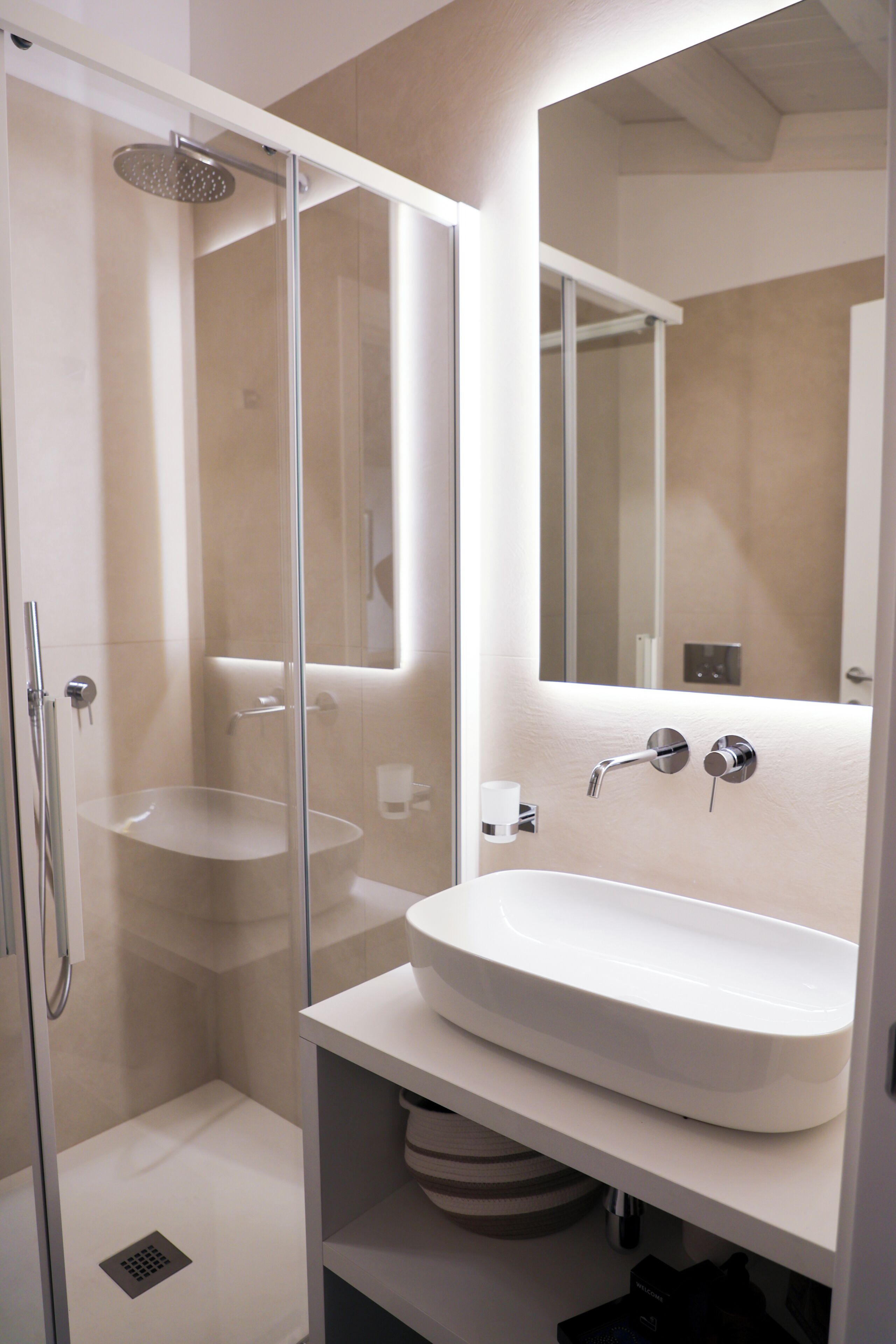 Une salle de bain moderne avec une douche à parois de verre, un lavabo blanc et un miroir.