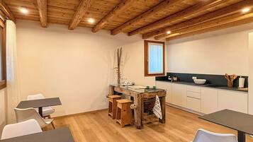 Un espace repas avec un plafond en bois, une table en verre et des chaises blanches.